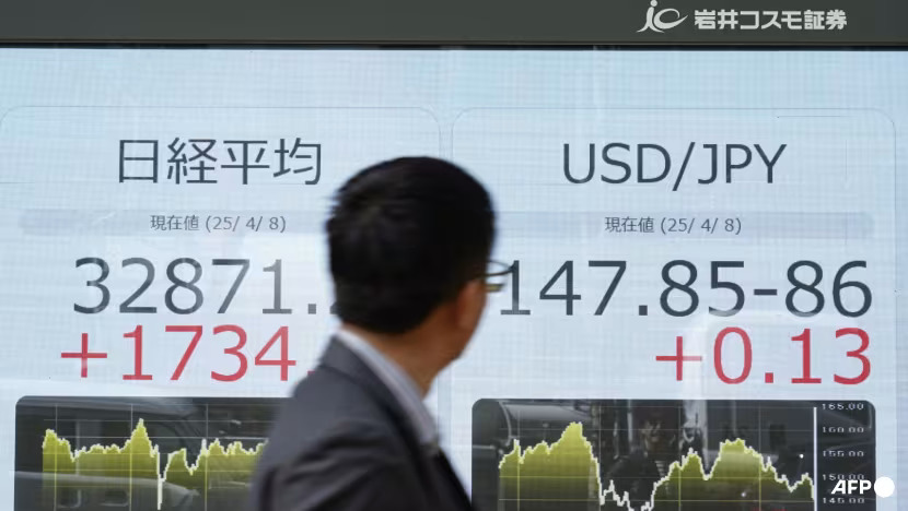 A man looks at an electronic board showing the numbers of the Nikkei Stock Average (left) on the Tokyo Stock Exchange and a USD/JPY foreign exchagne board (right) along a street in Tokyo on Apr 8, 2025. (Photo: AFP/Kazuhiro Nogi)