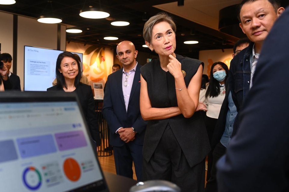 Minister for Digital Development and Information Josephine Teo (second from right) and Senior Parliamentary Secretary for Culture, Community and Youth Goh Hanyan (left) looking at live demonstrations of AI technologies transforming finance and supply chain management at PwC's flagship AI Hub on Aug 11.  ST PHOTO: AZMI ATHNI