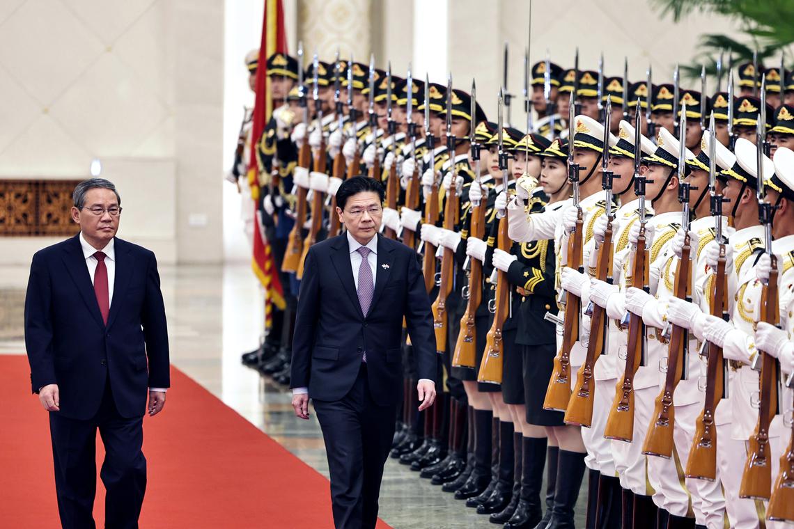 Chinese Premier Li Qiang (left) and Singapore Prime Minister Lawrence Wong review the honour guard during a welcome ceremony at the North Hall of the Great Hall of the People in Beijing on June 23. ST PHOTO: KELVIN CHNG